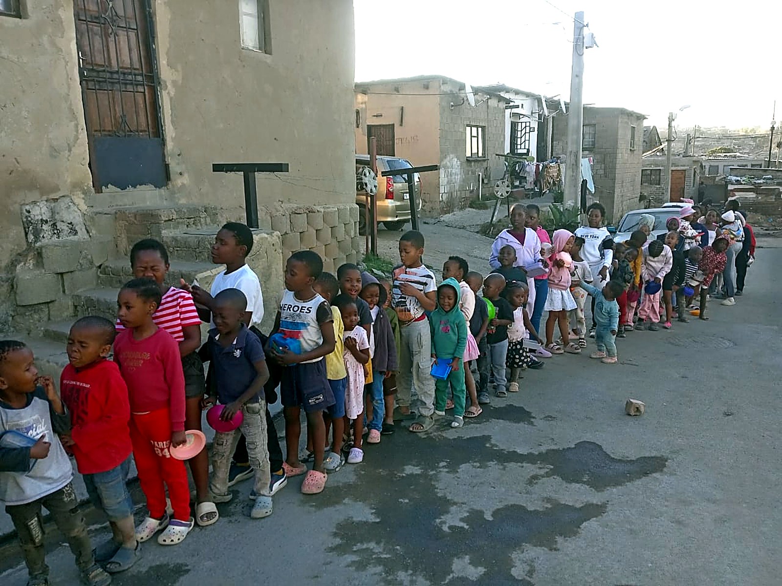 Children waiting in line for a meal outside homes in the community