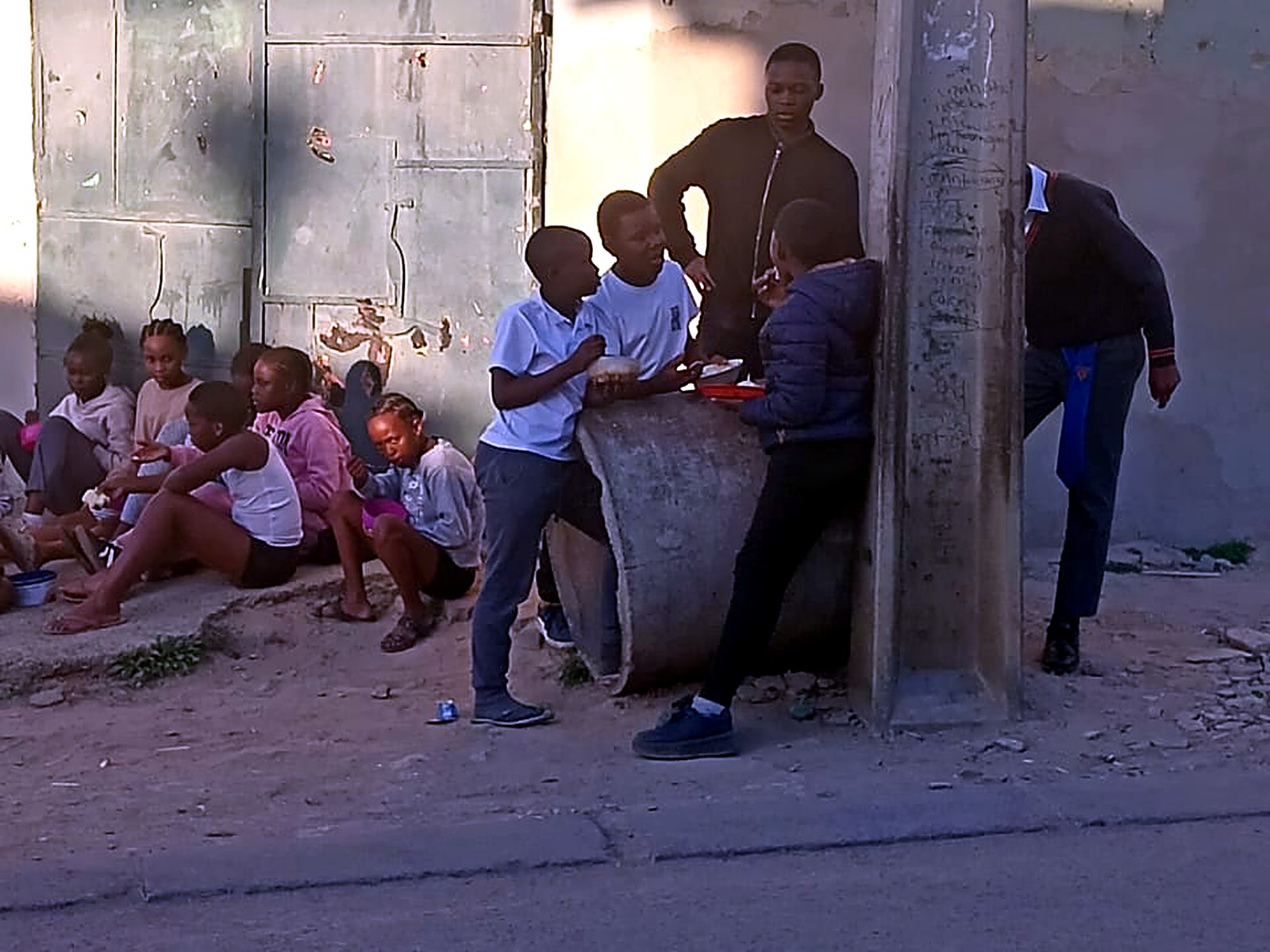 Children sharing a meal together at the roadside after a community feeding scheme